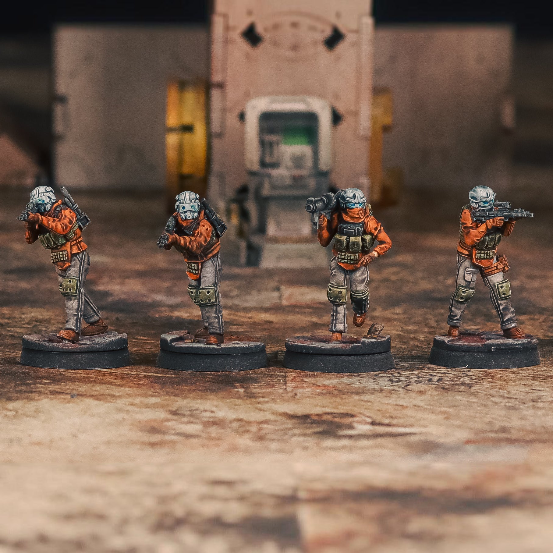 Four miniature figures in military gear on a textured surface with a blurred background
