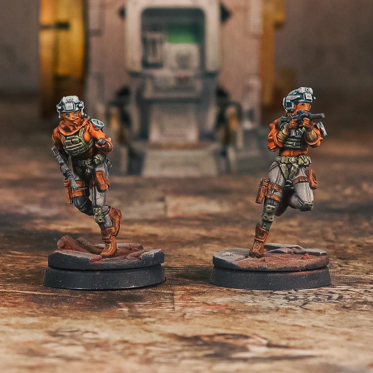 Two miniature figures in futuristic armor on a textured surface with a blurred background