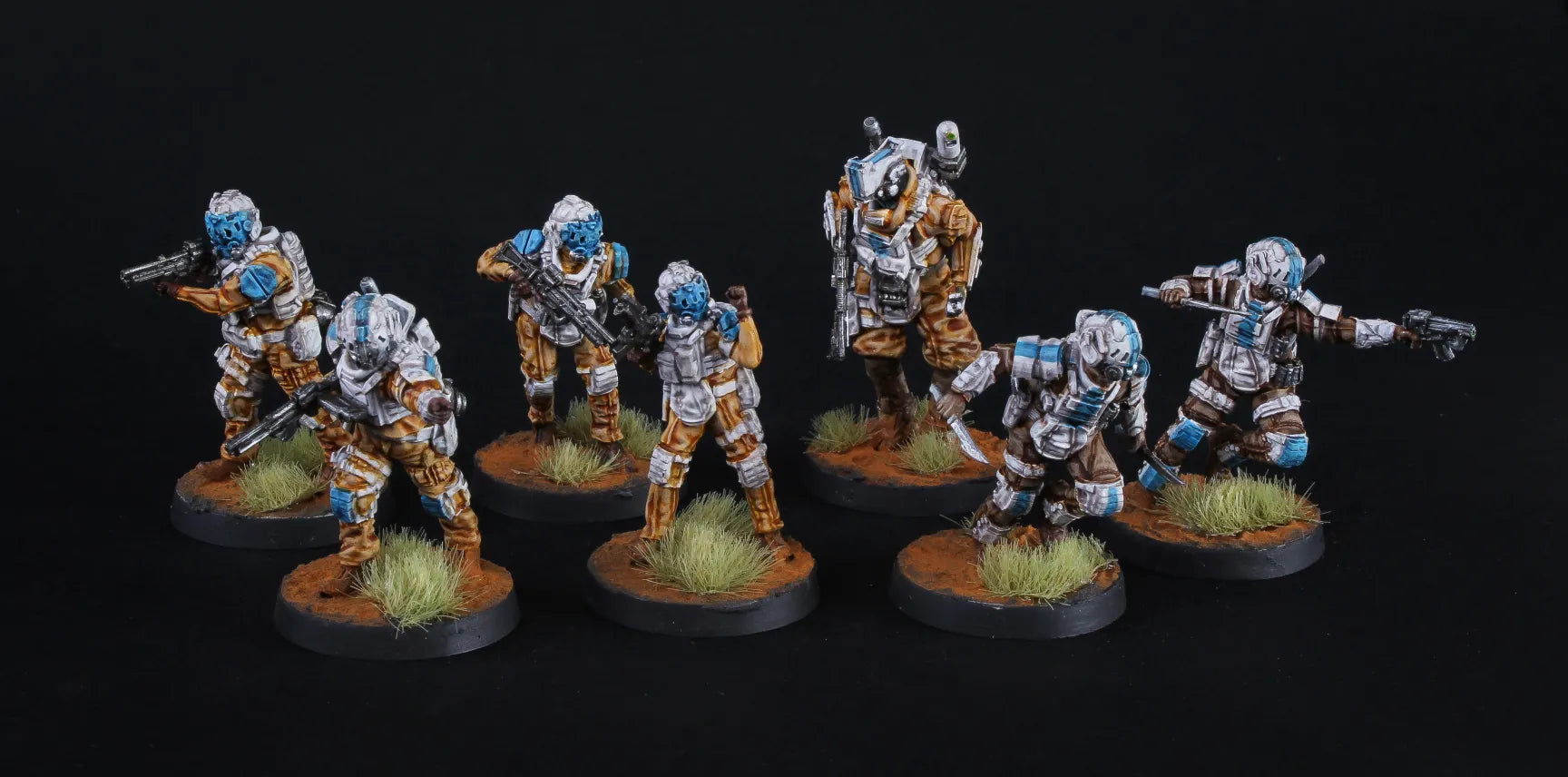 Seven miniature figures in futuristic armor on a dark background