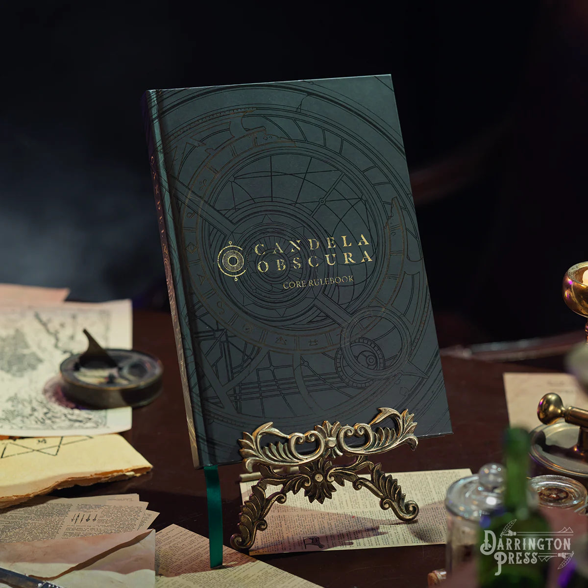 Dark blue book titled 'Candela Obscura' on a table with vintage items.